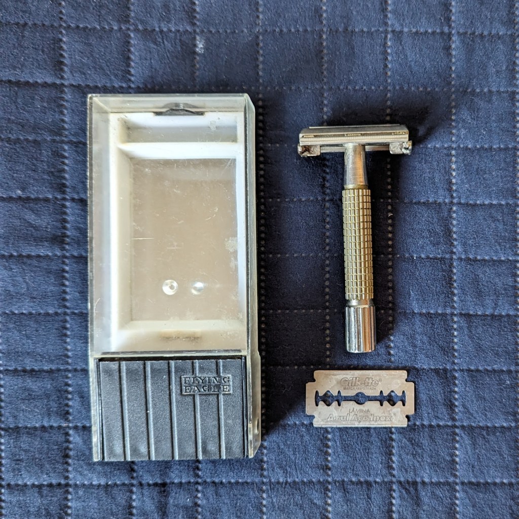 Caixa de aparelho de barbear de lâmina com espelho no fundo do lado esquerdo, aparelho de barbear de lâmina do lado direito, lâmina de barbear abaixo do aparelho