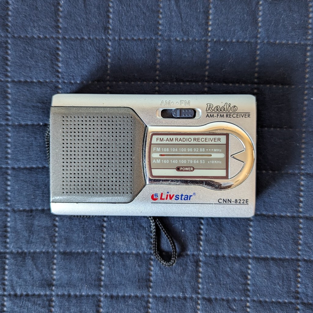 Rádio de pilha prateado sob fundo azul escuro